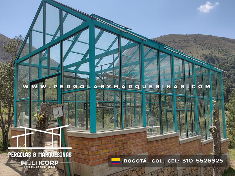 Pergolado con estructura turquesa y vidrio sobre base de ladrillo con vista a montanas cercana a Bogotá, Colombia. Multicorp Ingeniería SAS.