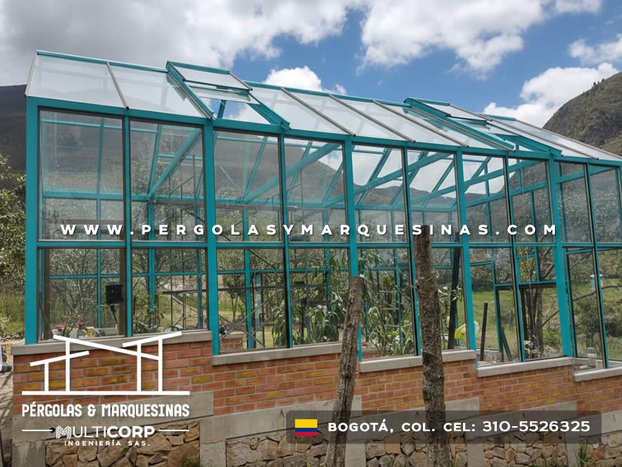 Cubierta con estructura turquesa y vidrio sobre base de ladrillo y muro de piedra en zona rural cercana a Bogotá, Colombia. Multicorp Ingeniería SAS.