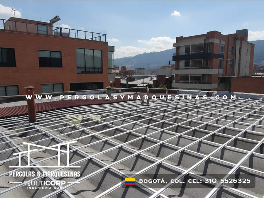 Pergola con estructura metalica blanca en cuadricula sobre terraza urbana con edificios cercanos en Bogotá, Colombia. Multicorp Ingeniería SAS.
