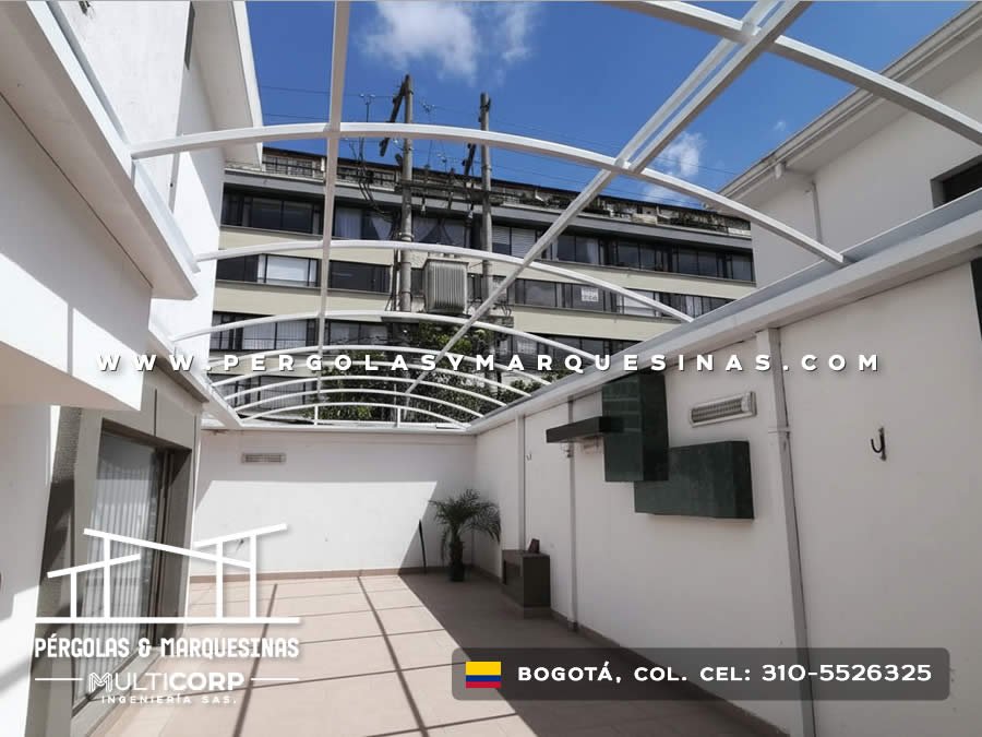 Domo con estructura curva blanca y policarbonato en patio urbano entre edificios en Bogotá, Colombia. Multicorp Ingeniería SAS.