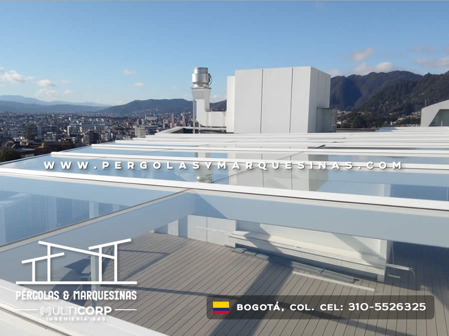 Domo transparente con estructura metálica blanca sobre deck de madera en terraza de ático con vista a cerros en Bogotá, Colombia. Multicorp Ingeniería SAS.