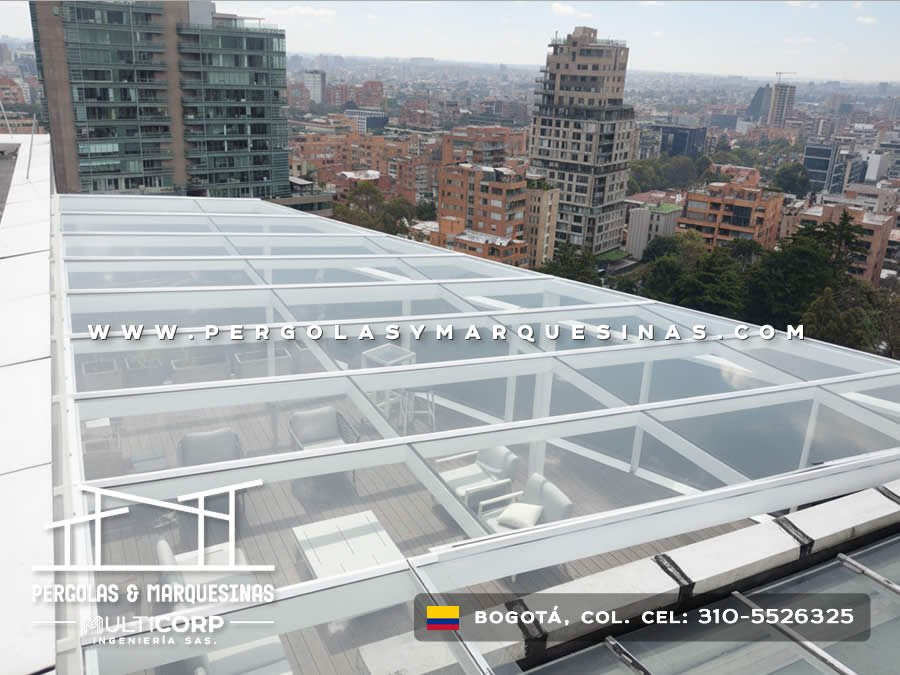 Techo de vidrio con perfiles metálicos blancos sobre deck de madera en terraza de ático urbano en Bogotá, Colombia. Multicorp Ingeniería SAS.