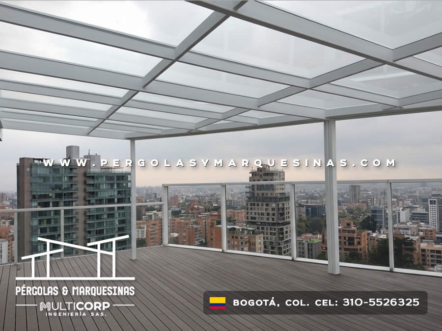 Techo de vidrio templado con perfiles blancos barandal de vidrio y deck de madera en terraza de ático en Bogotá, Colombia. Multicorp Ingeniería SAS.