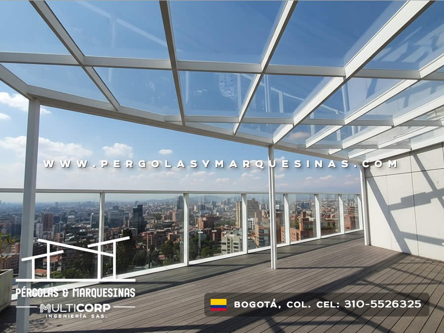Pérgola de vidrio con perfiles metálicos blancos barandales transparentes y deck en terraza de ático con vista panorámica en Bogotá, Colombia. Multicorp Ingeniería SAS.