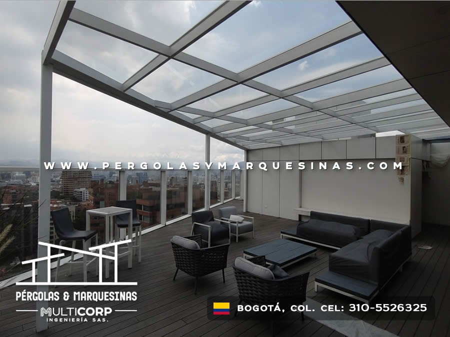 Cubierta de vidrio con estructura metálica gris muebles lounge y deck de madera en terraza de ático en Bogotá, Colombia. Multicorp Ingeniería SAS.
