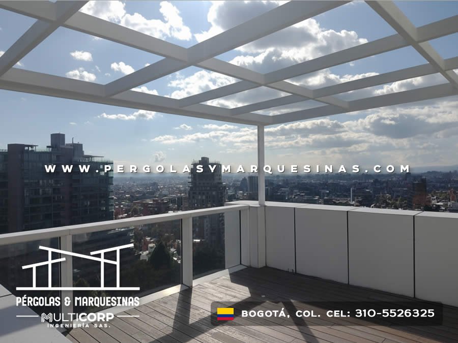 Pérgola con techo de vidrio estructura blanca cerramientos laterales y deck de madera en terraza de ático en Bogotá, Colombia. Multicorp Ingeniería SAS.