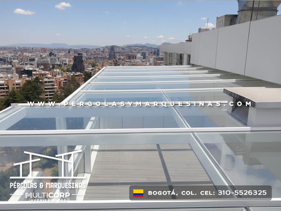 Cubierta de vidrio templado con perfiles blancos sobre terraza de ático con vista a cerros y ciudad en Bogotá, Colombia. Multicorp Ingeniería SAS.