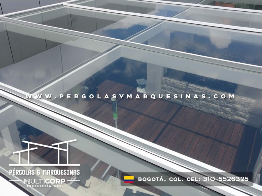 Techo de vidrio con estructura blanca sobre deck de madera visto desde arriba en terraza de ático en Bogotá, Colombia. Multicorp Ingeniería SAS.