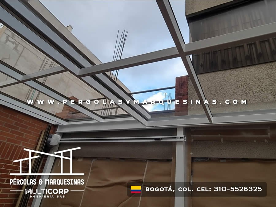 Cubierta retráctil con techo de vidrio y perfiles metálicos grises sobre terraza residencial en Bogotá, Colombia. Multicorp Ingeniería SAS.
