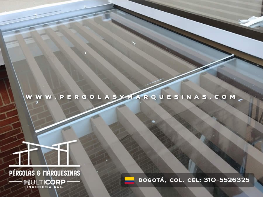 Techo corredizo de vidrio con rieles metálicos blancos sobre patio interior residencial en Bogotá, Colombia. Multicorp Ingeniería SAS.
