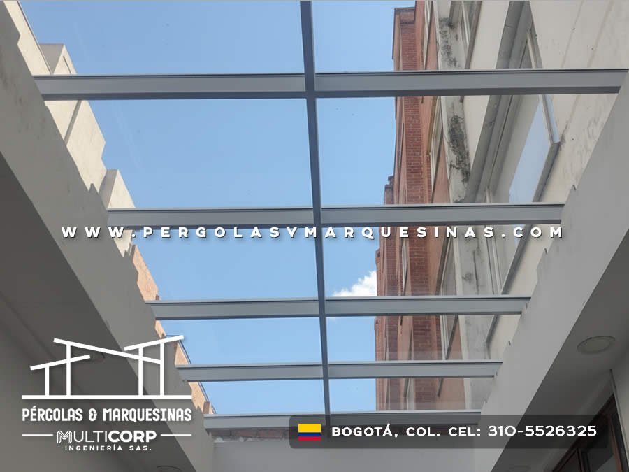 Lucernario de vidrio con perfiles metálicos grises sobre espacio interior visto desde abajo en Bogotá, Colombia. Multicorp Ingeniería SAS.