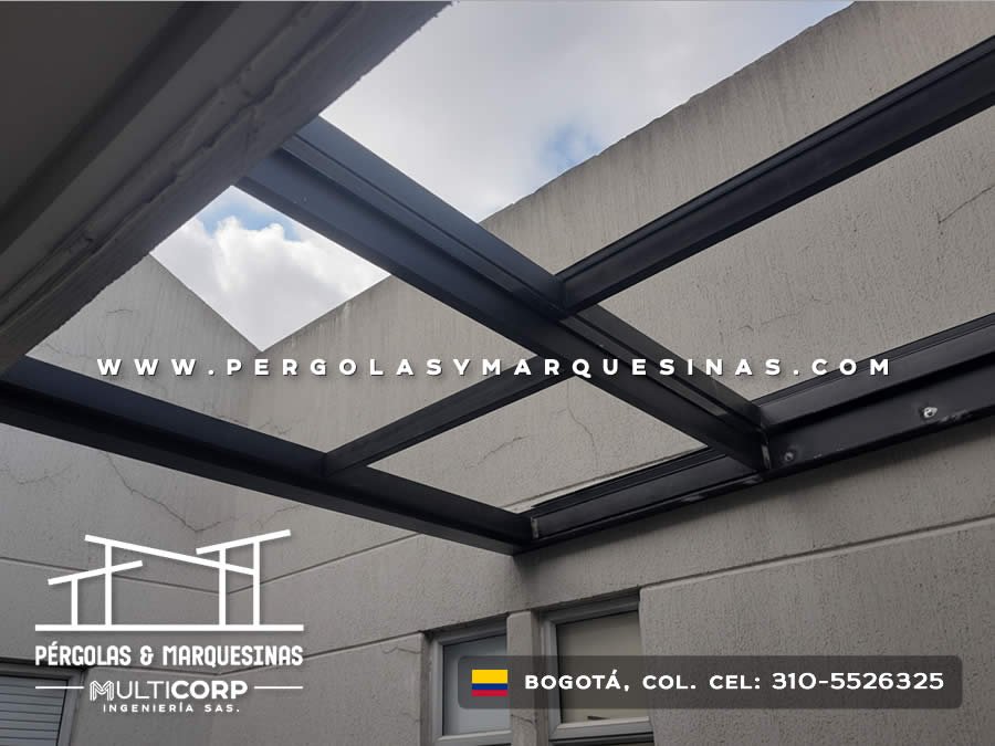 Cubierta retráctil con estructura metalica negra en posición abierta sobre patio interior en Bogotá, Colombia. Multicorp Ingeniería SAS.