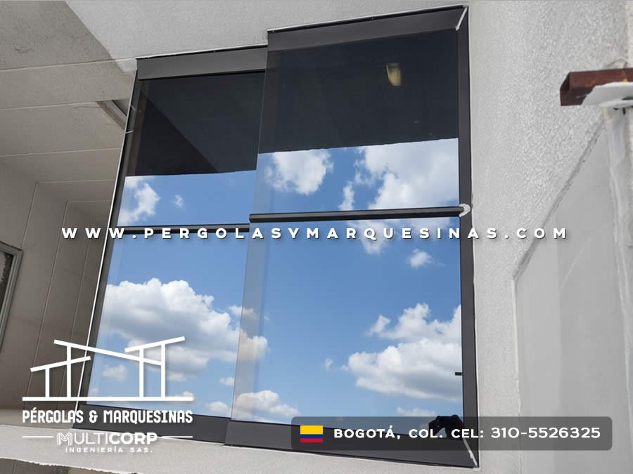 Ventana de vidrio ahumado con marco metalico negro y sistema de apertura vertical en fachada en Bogotá, Colombia. Multicorp Ingeniería SAS.