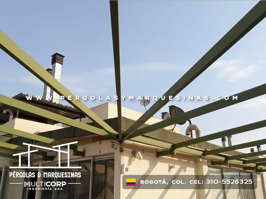 Pergola con vigas metalicas en tono verde sobre terraza con chimeneas en edificio residencial en Bogotá, Colombia. Multicorp Ingeniería SAS.