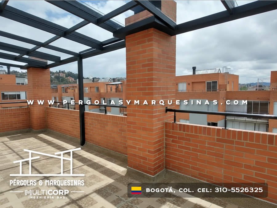 Pergola con techo de vidrio estructura negra y muros de ladrillo en terraza con vista a cerros en Bogotá, Colombia. Multicorp Ingeniería SAS.
