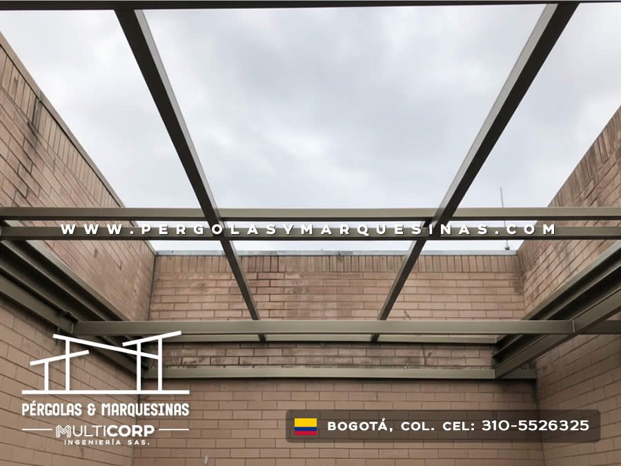 Pergola con techo de vidrio estructura metalica y muros de ladrillo en patio interior residencial en Bogotá, Colombia. Multicorp Ingeniería SAS.