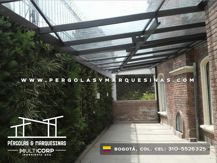 Pergola con techo de vidrio estructura negra y pasillo lateral en casa con jardin vertical en Bogotá, Colombia. Multicorp Ingeniería SAS.