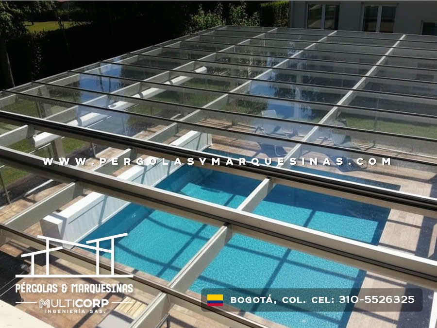 Cubierta de vidrio con estructura metalica sobre piscina con vista a jardin en casa residencial en Bogotá, Colombia. Multicorp Ingeniería SAS.