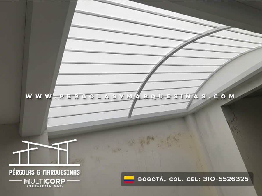 Techo de policarbonato con arcos metálicos y estructura gris vista desde interior de espacio residencial en Bogotá, Colombia. Multicorp Ingeniería SAS.